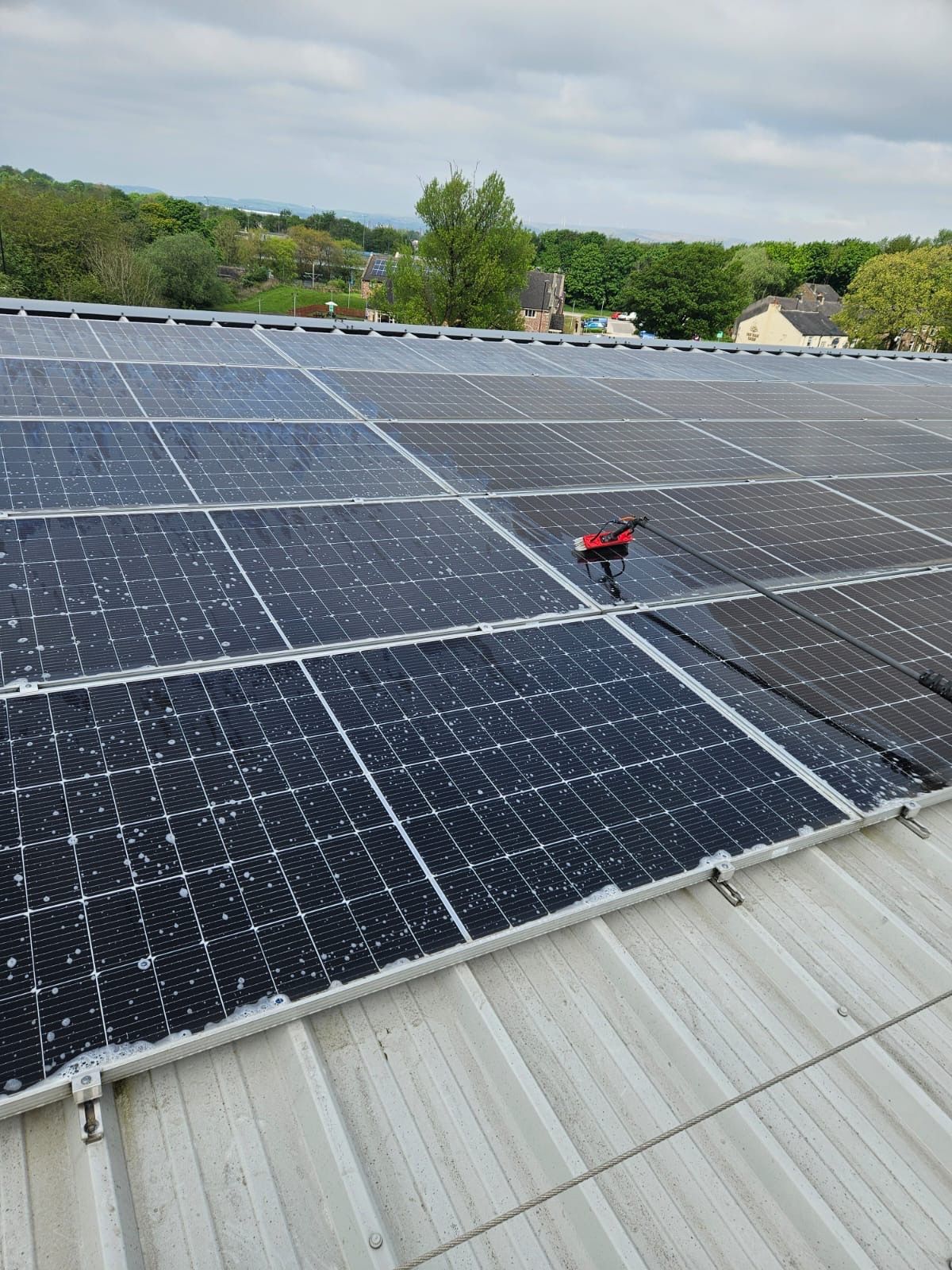 Large commercial solar array being cleaned from cherry picker platform