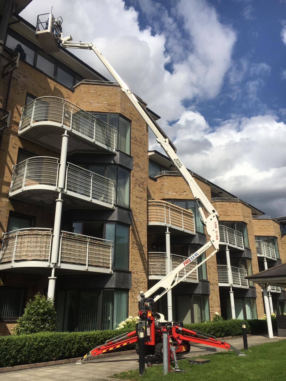 ProClean Access spider platform fully extended at a modern multi-storey residential block against blue sky